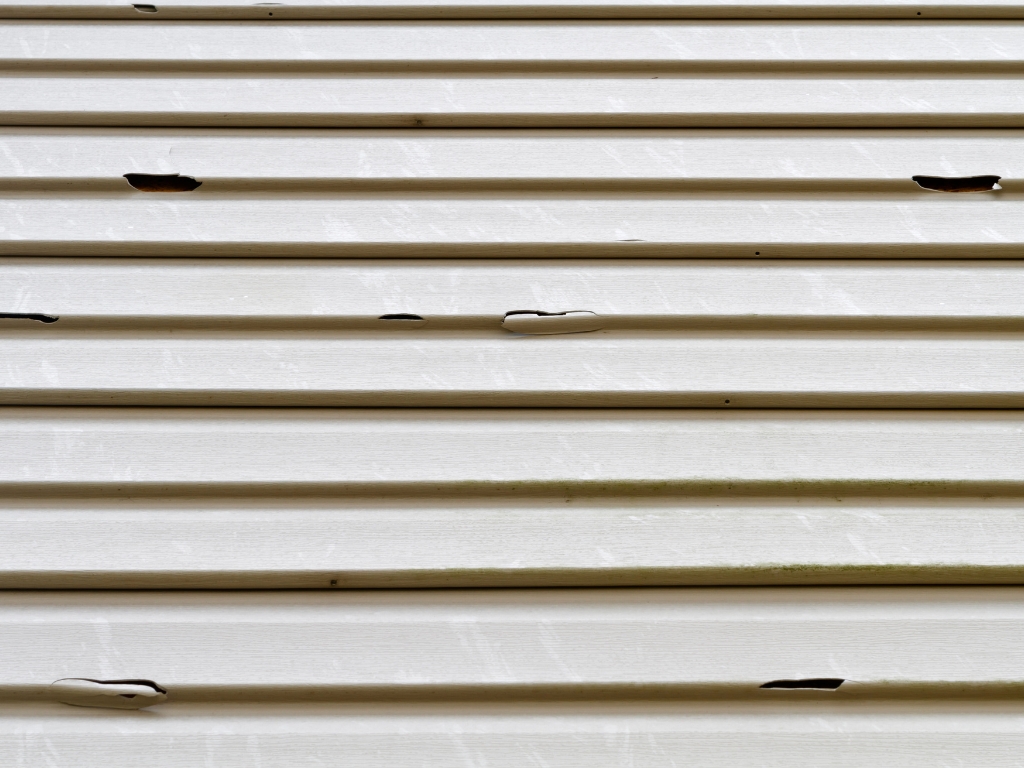 Damaged siding with visible cracks.